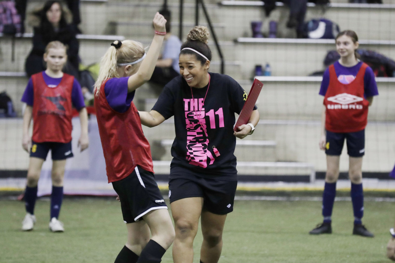 Desiree Scott celebrates on field with a participant of her annual KidSport soccer camp