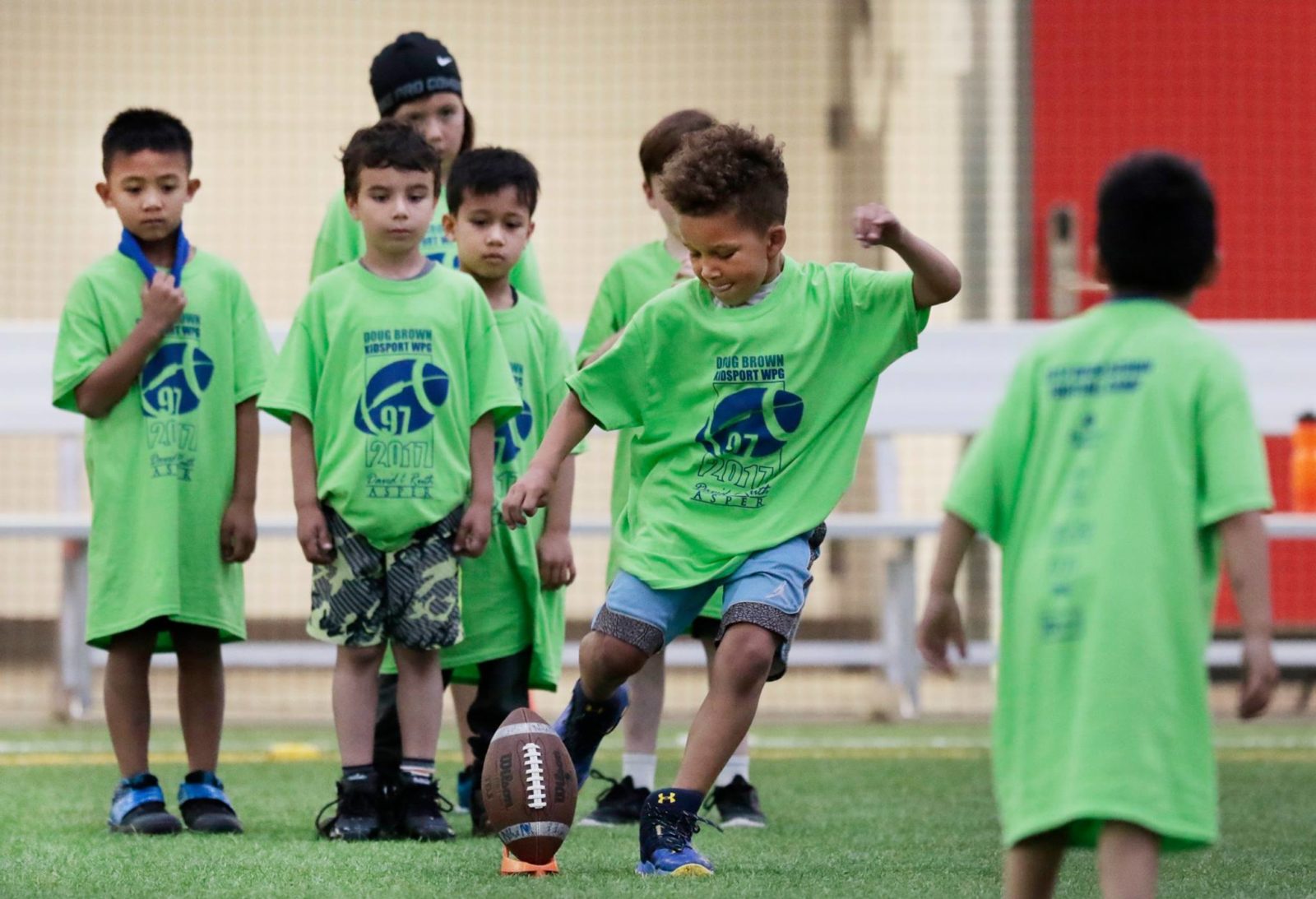 Kid kicking football at the Doug Brown KidSport Annual Football Camp