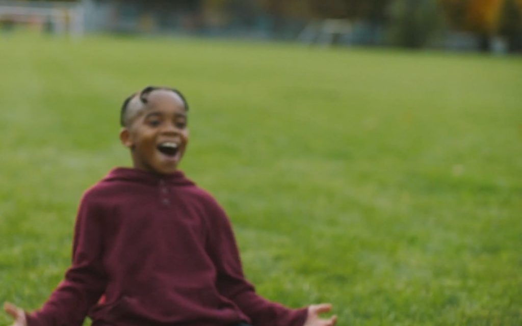 A young boy sliding on the grass soccer field after scoring a goal